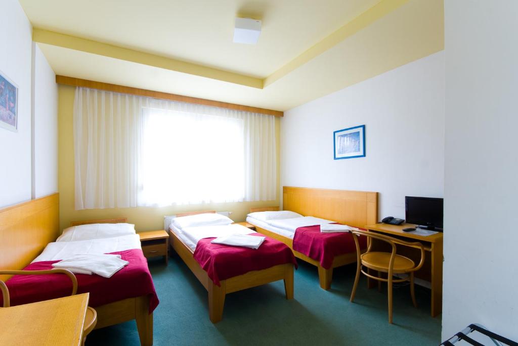 a hospital room with three beds and a desk at Hotel Smaragd in Prague
