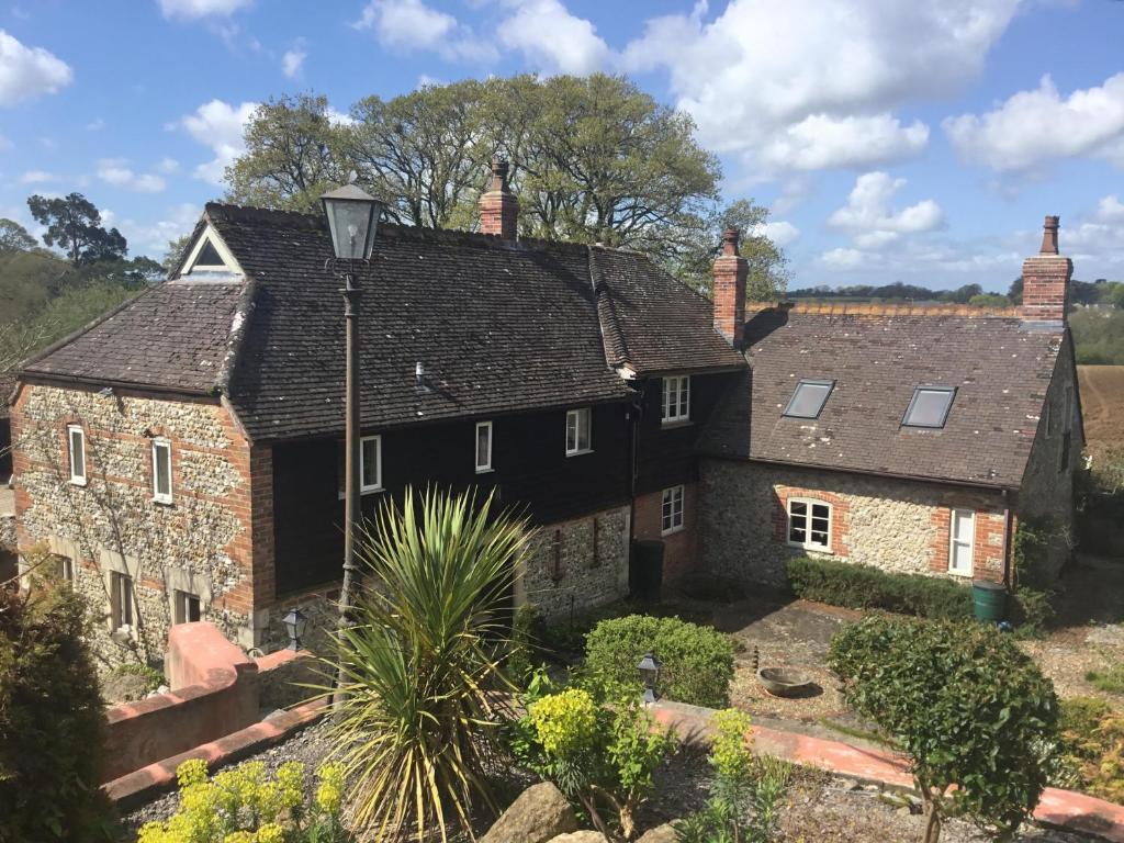 une ancienne maison en pierre avec un toit noir dans l'établissement Gorse Farm House B&B, à Sturminster Newton