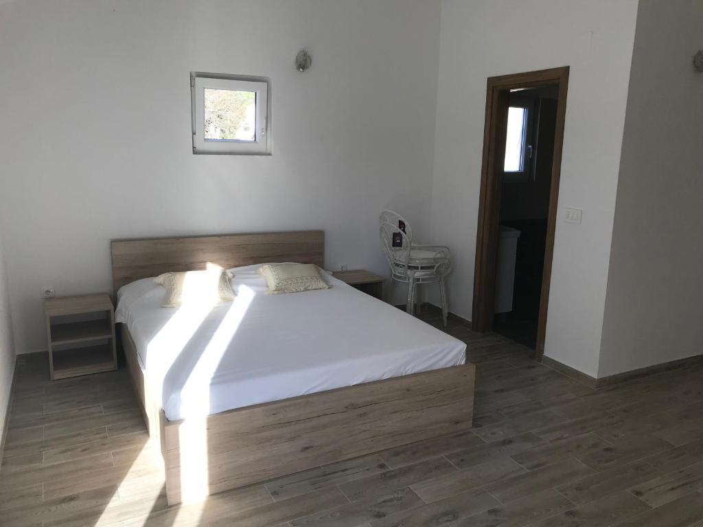 a bedroom with a bed with white sheets and a window at Apartments Sanja in Jezera