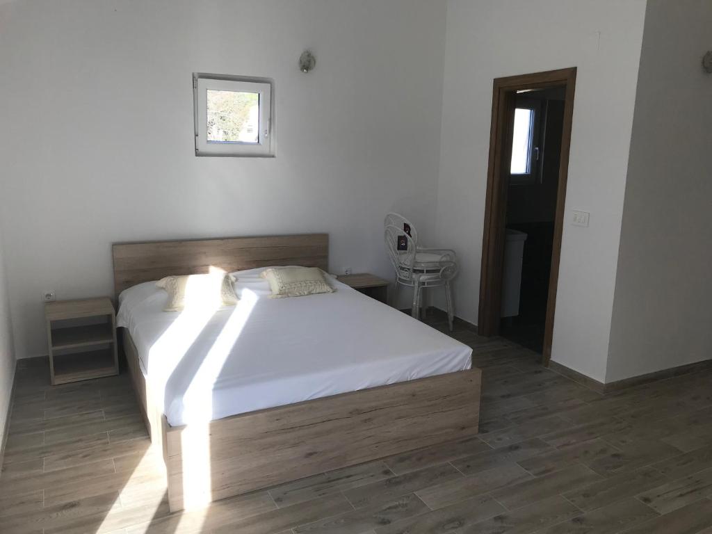 Apartments Sanja في يزيرا: غرفة نوم بسرير وملاءات بيضاء ونافذة