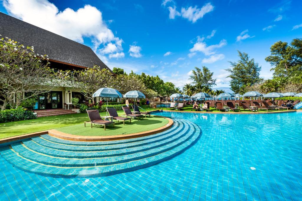een zwembad in een resort met stoelen en parasols bij Chada Lanta Beach Resort - SHA Extra Plus in Koh Lanta