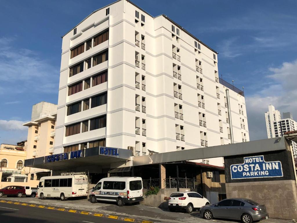 un gran edificio blanco con coches estacionados frente a él en Hotel Costa Inn, en Panamá