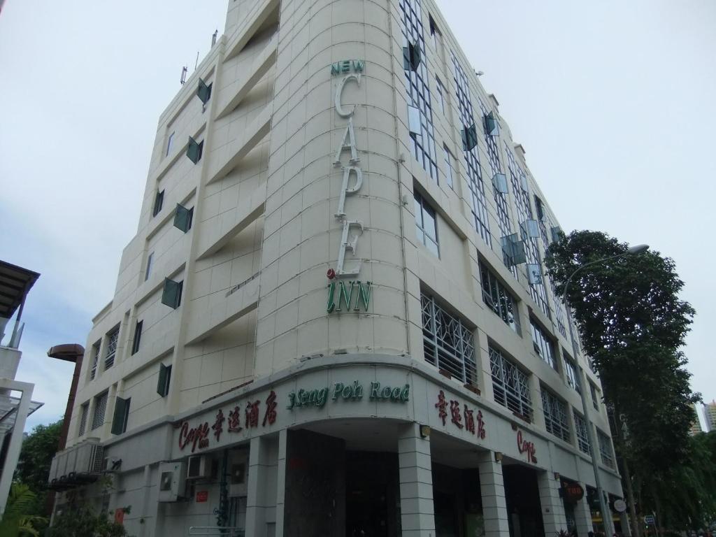 un grande edificio bianco con scritte sopra di New Cape Inn a Singapore