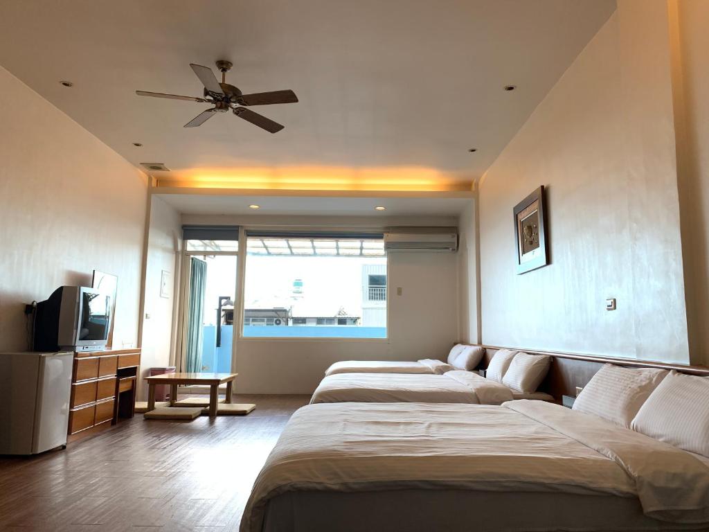 a bedroom with three beds and a ceiling fan at Jia Ying Beach Resort B&amp;B in Toucheng