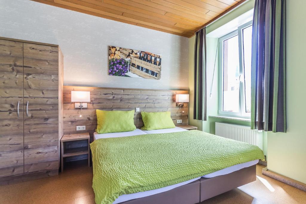 Un dormitorio con una cama con sábanas verdes y una ventana en Altes Schulhaus en Zeltingen-Rachtig