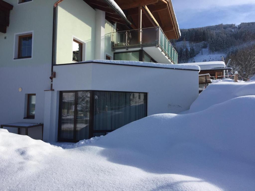 une maison recouverte de neige avec un tas de neige dans l'établissement Ferienwohnung Steiner, à Tulfes
