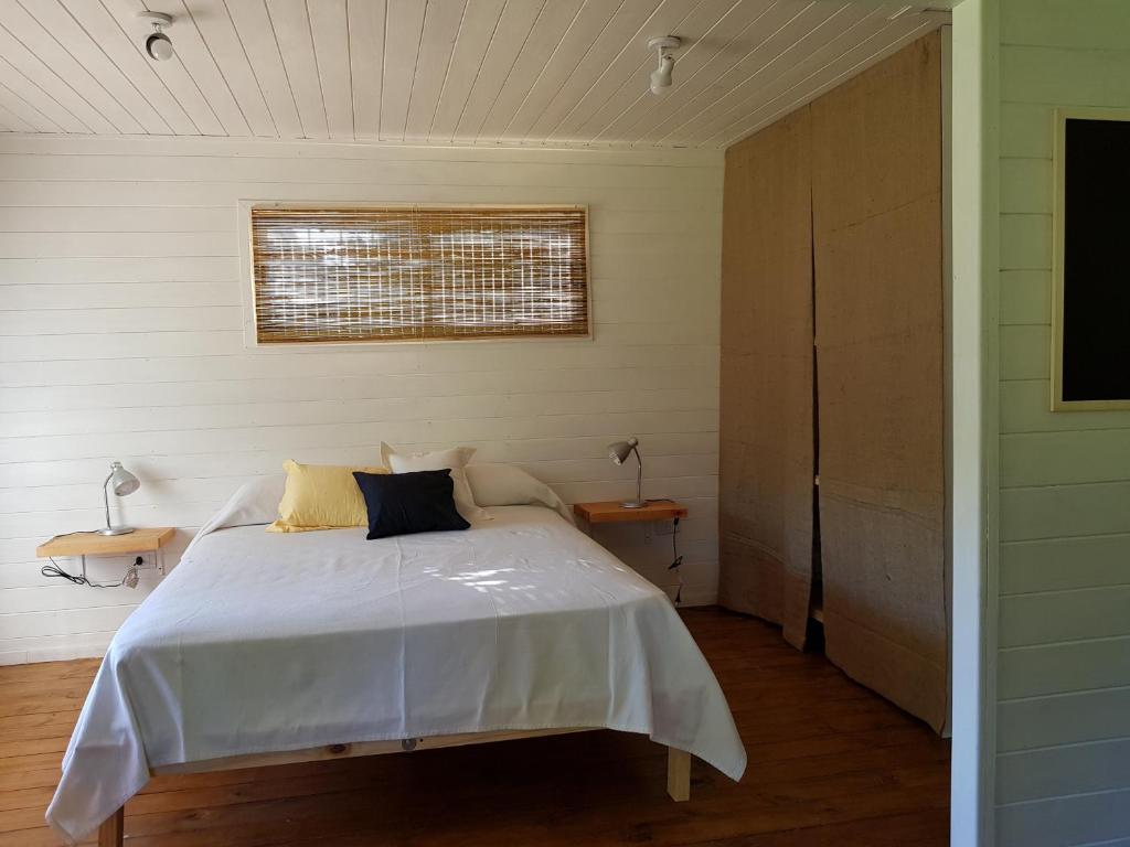 1 dormitorio con cama blanca y ventana en Cabaña Los Juncos en Tigre