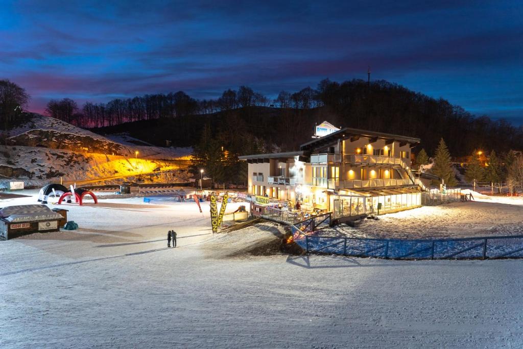 un lodge de esquí en la nieve por la noche en Hotel Laghetto en Prato Nevoso