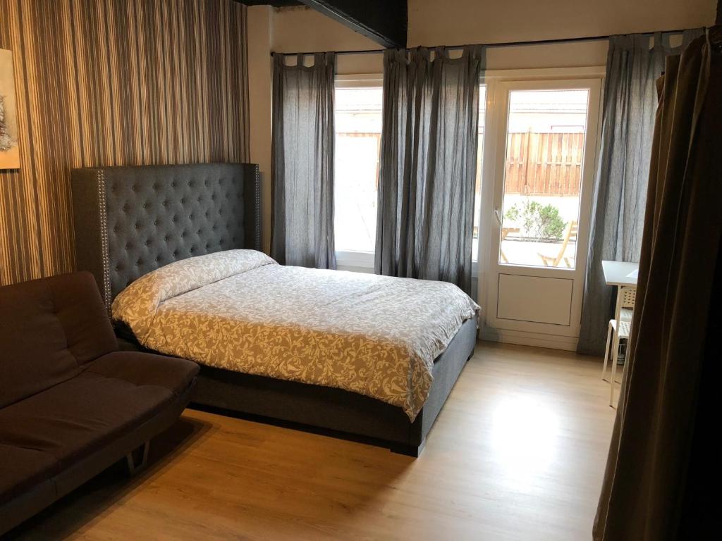 1 dormitorio con cama, sofá y ventana en Estudios Bilbao Deusto, en Bilbao
