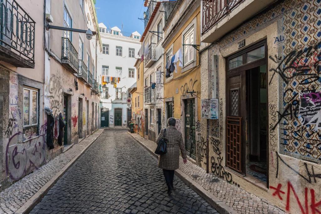 a woman walking down a street in an alley at Atalaia Place - Bairro Alto, Lisbon City Center in Lisbon