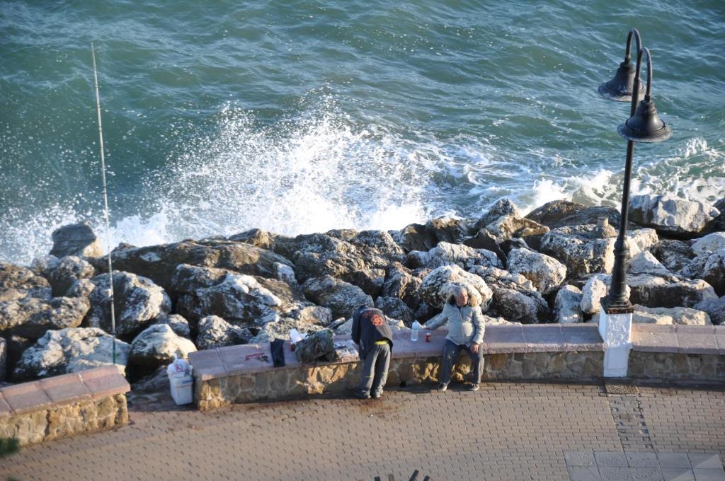 two people sitting on a bench by the water at Studio Vue Mer in Torremolinos