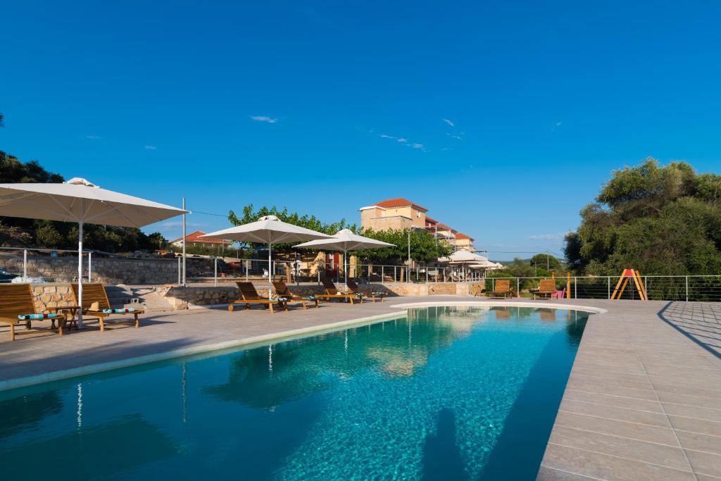 a swimming pool with chairs and umbrellas and a playground at Dialiskari Villas in Marathopoli