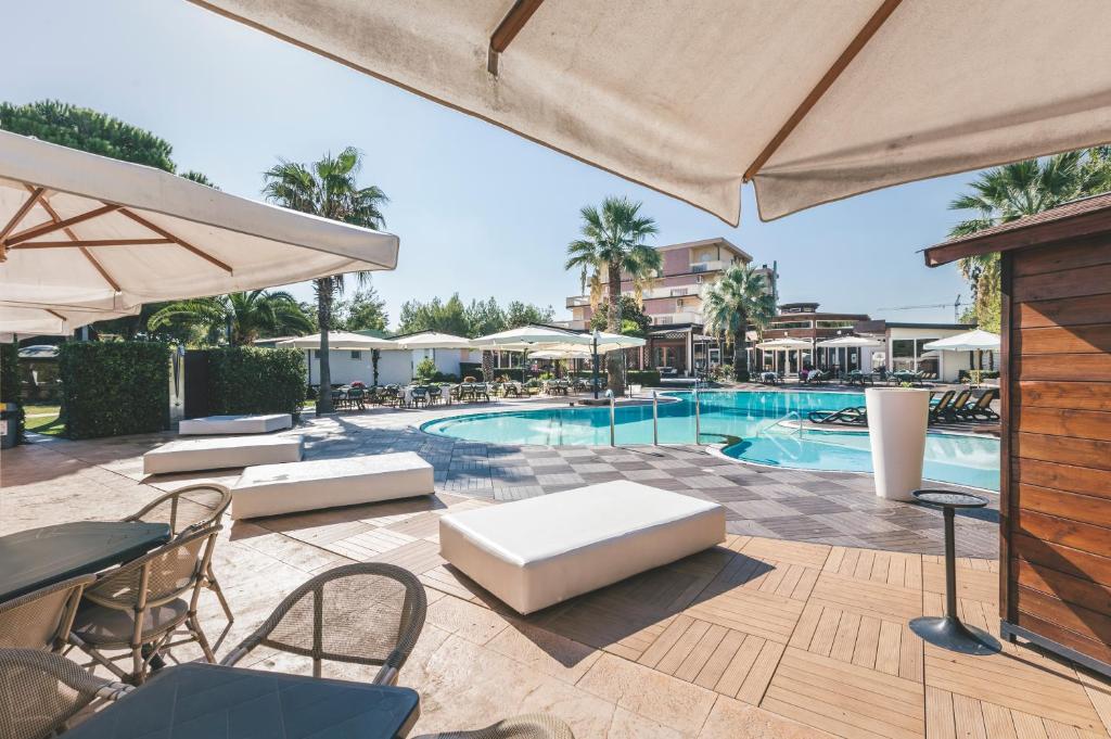 een zwembad met tafels en stoelen en een parasol bij Hotel Acquario in Vasto