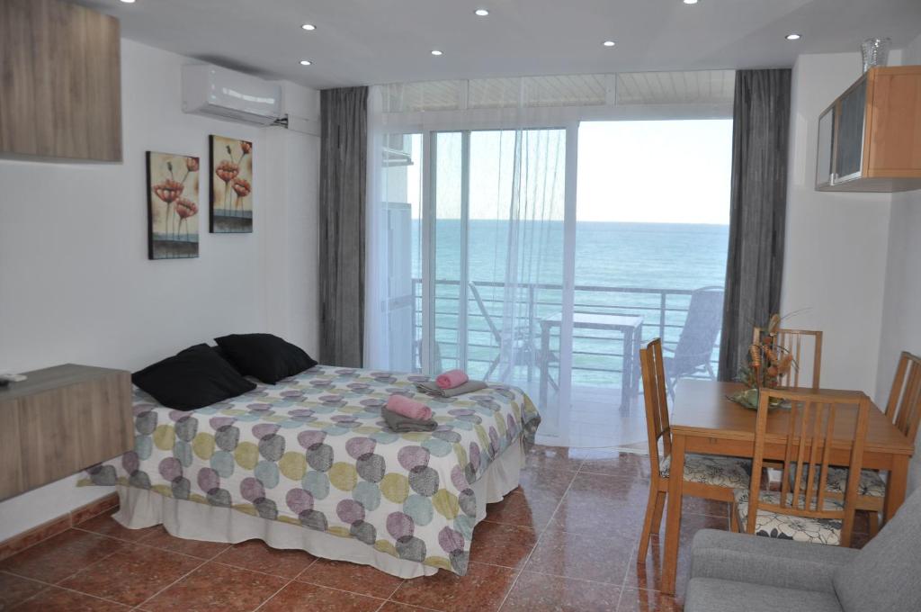 a bedroom with a bed and a table and a balcony at Studio Vue Mer in Torremolinos