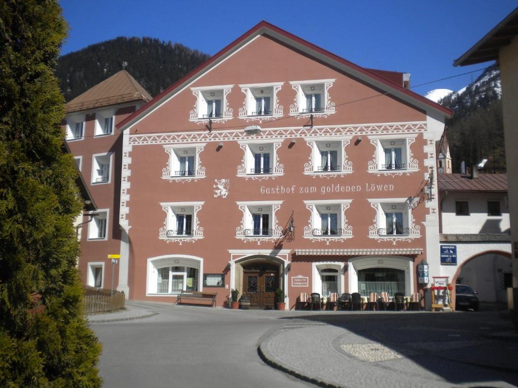 een groot roze gebouw midden in een straat bij Gasthof zum goldenen Löwen in Nauders