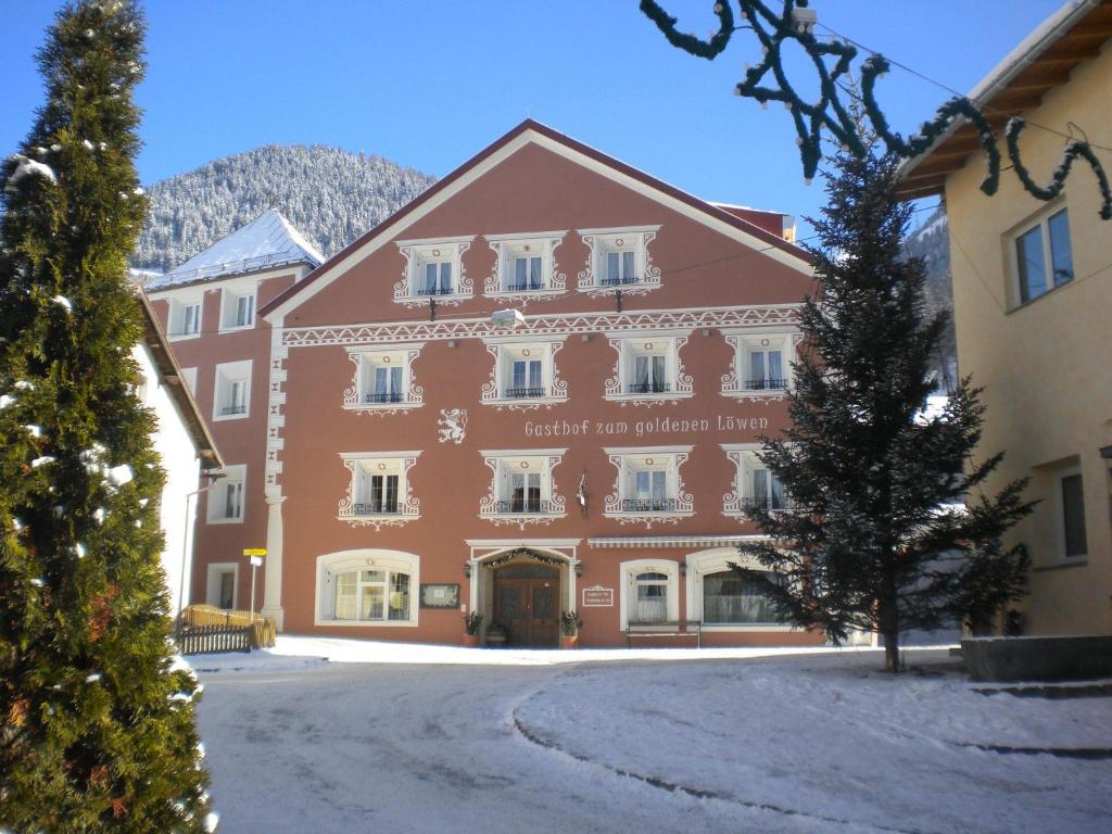 ナウダースにあるGasthof zum goldenen Löwenの目の前に木が立つ大きな赤い建物
