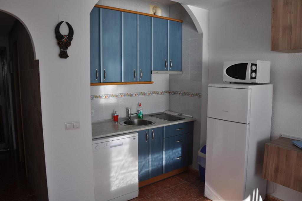 a kitchen with blue cabinets and a sink and a refrigerator at Studio Vue Mer in Torremolinos