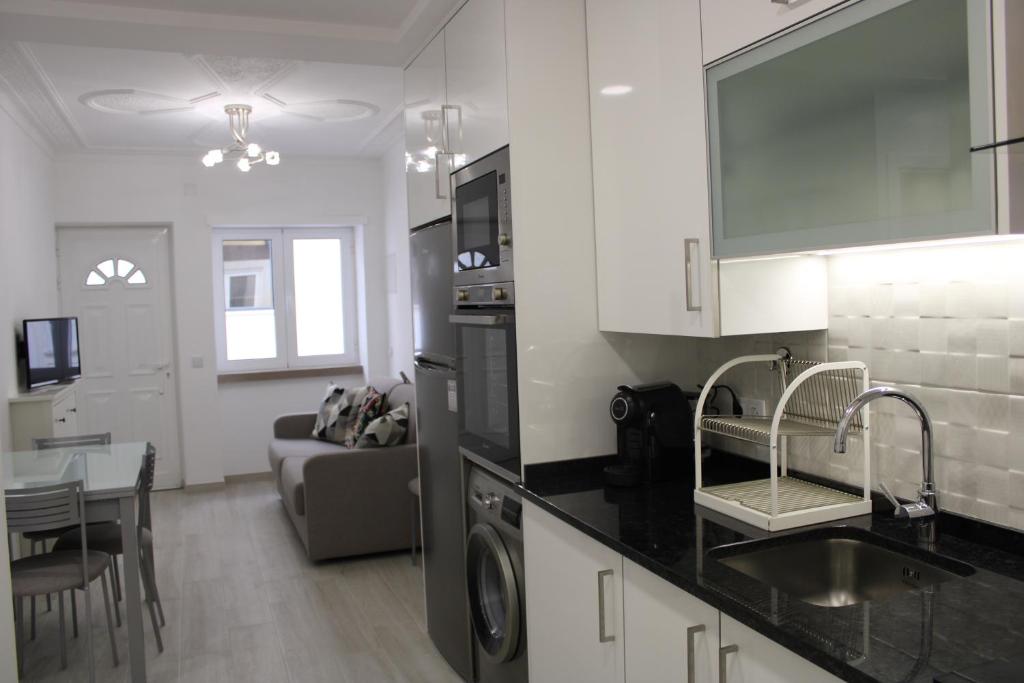 a kitchen with black counter tops and a living room at Sun & Wave Apartment II in Nazaré