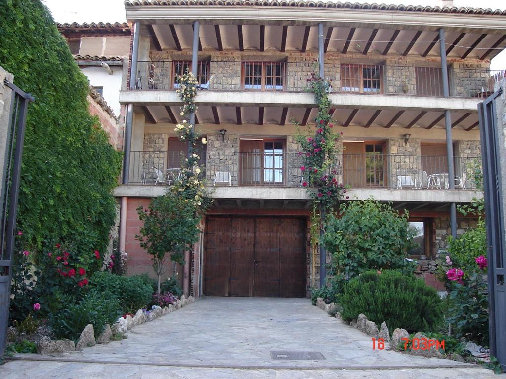 uma casa grande com uma porta de madeira e flores em Apartamentos el Portal em Gea de Albarracín