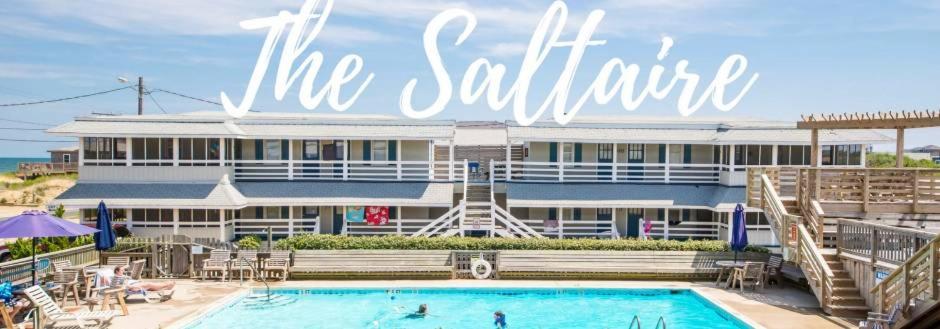 a hotel with a swimming pool in front of a building at Saltaire Cottages in Kitty Hawk Beach