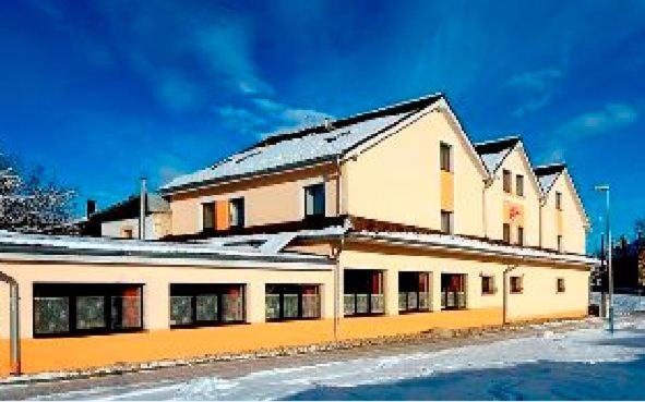 a large white building with snow on the ground at Penzión Valentína in Poprad