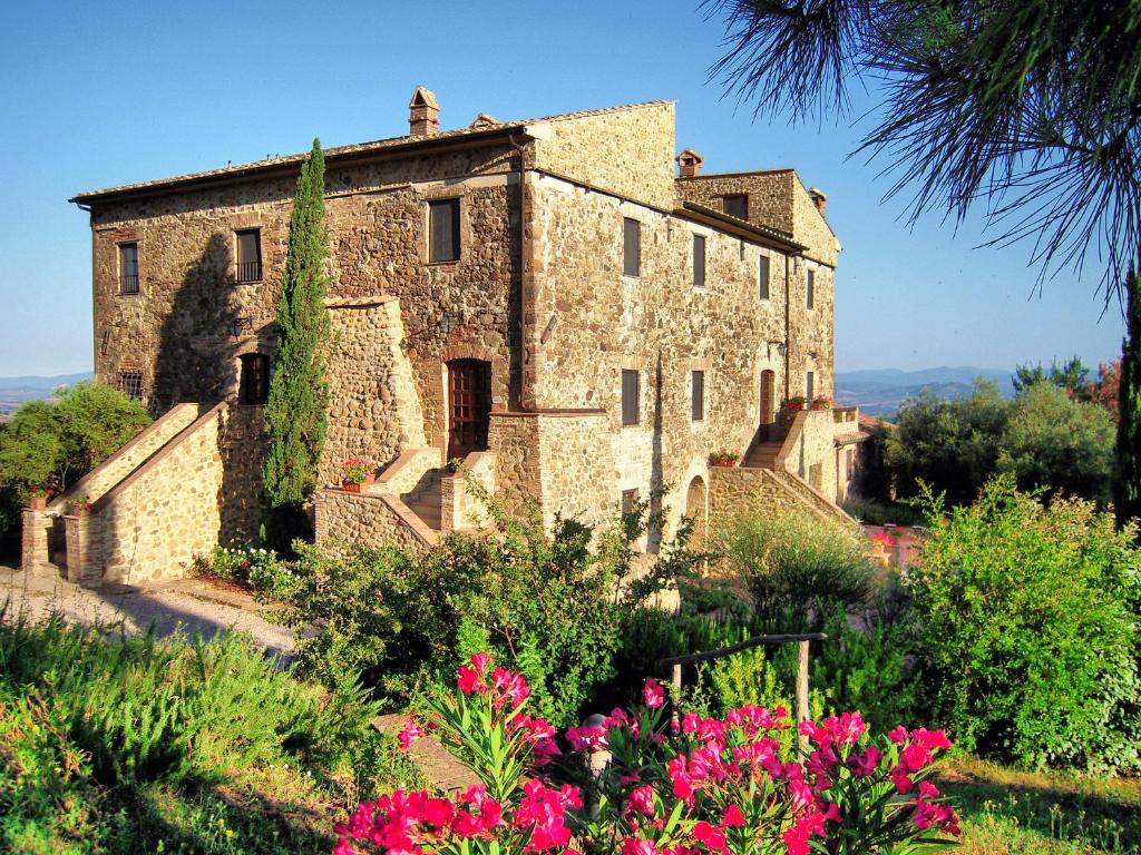 an old stone building with flowers in front of it at Tenuta Fattoria Vecchia in Scansano