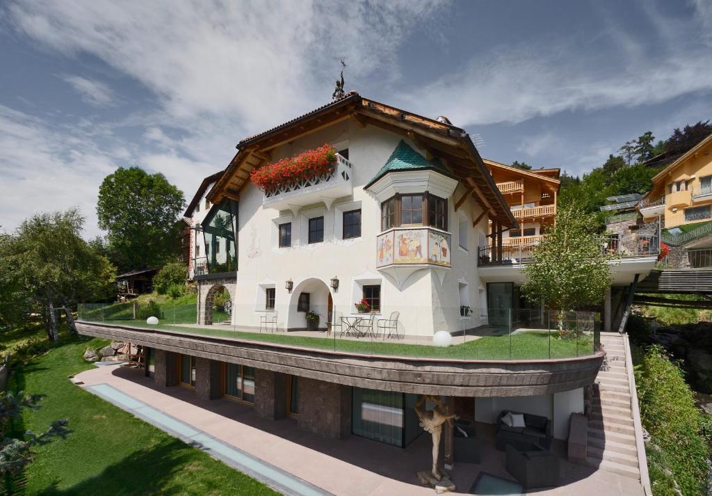 een groot wit huis met een dak bij Villa Schmalzl in Ortisei