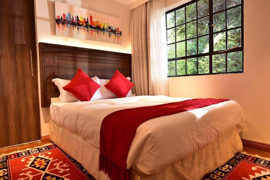 a bedroom with a bed with red pillows and a window at Palm Valley in Nairobi
