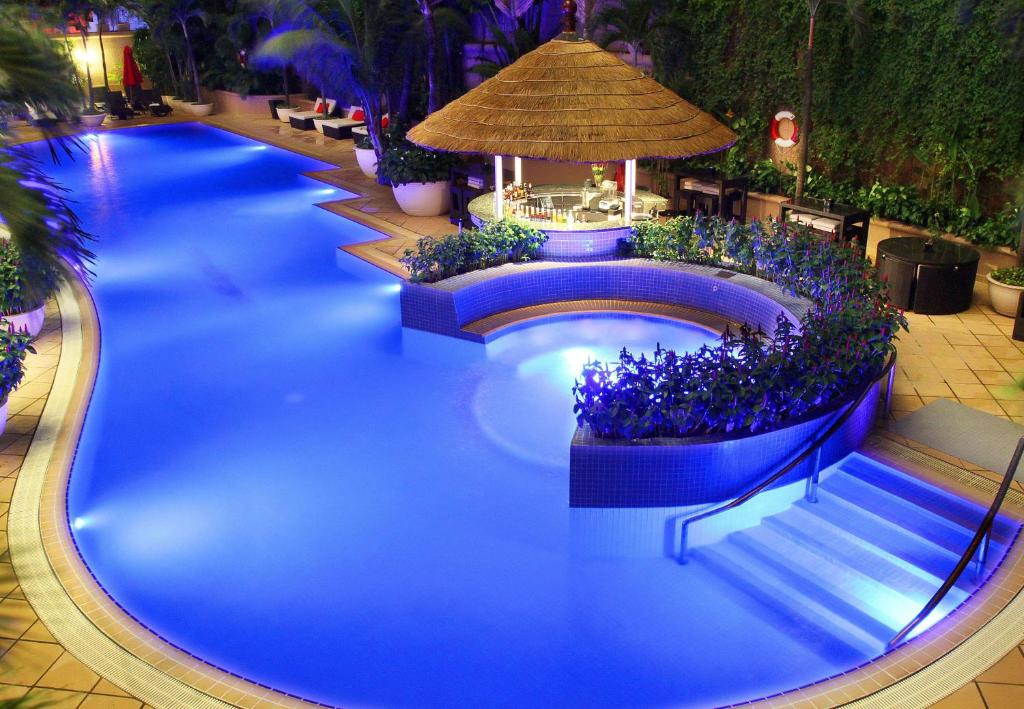 a large swimming pool with blue water and blue flowers at Caravelle Saigon in Ho Chi Minh City