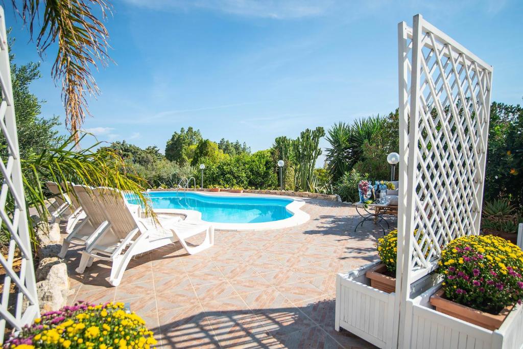 een witte poort die leidt naar een zwembad met stoelen en bloemen bij Villa La Randa in Castellammare del Golfo