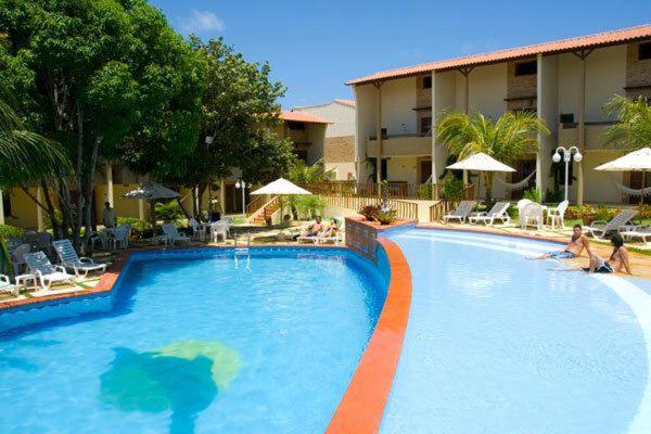 ein großer Swimmingpool in einem Hotel mit Leuten um ihn herum in der Unterkunft RESORT SOLAR PIPÁ CASA 24 in Pipa