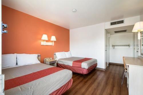 a hotel room with two beds and an orange wall at Motel 6 Wendover in Wendover