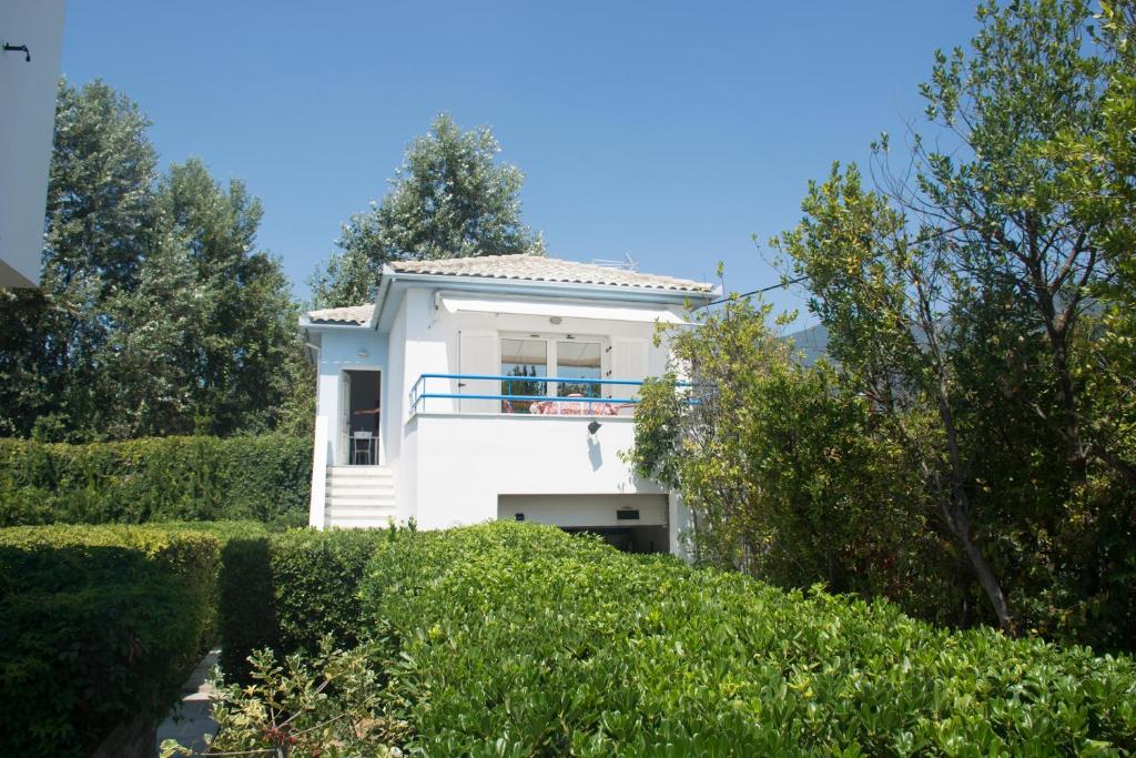 una casa blanca en una colina con arbustos en Romantic Seafront Studio - Dream Garden, en Platanidia