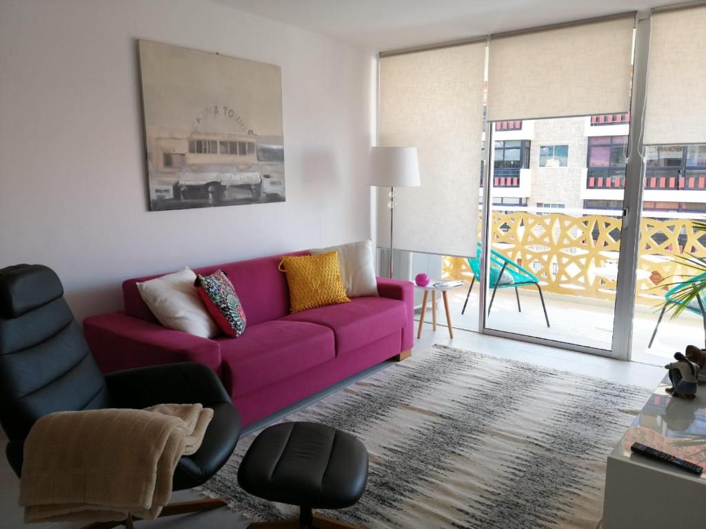 ein Wohnzimmer mit einem lila Sofa und einem Fenster in der Unterkunft Apartamento en Bajamar -Tenerife in Bajamar