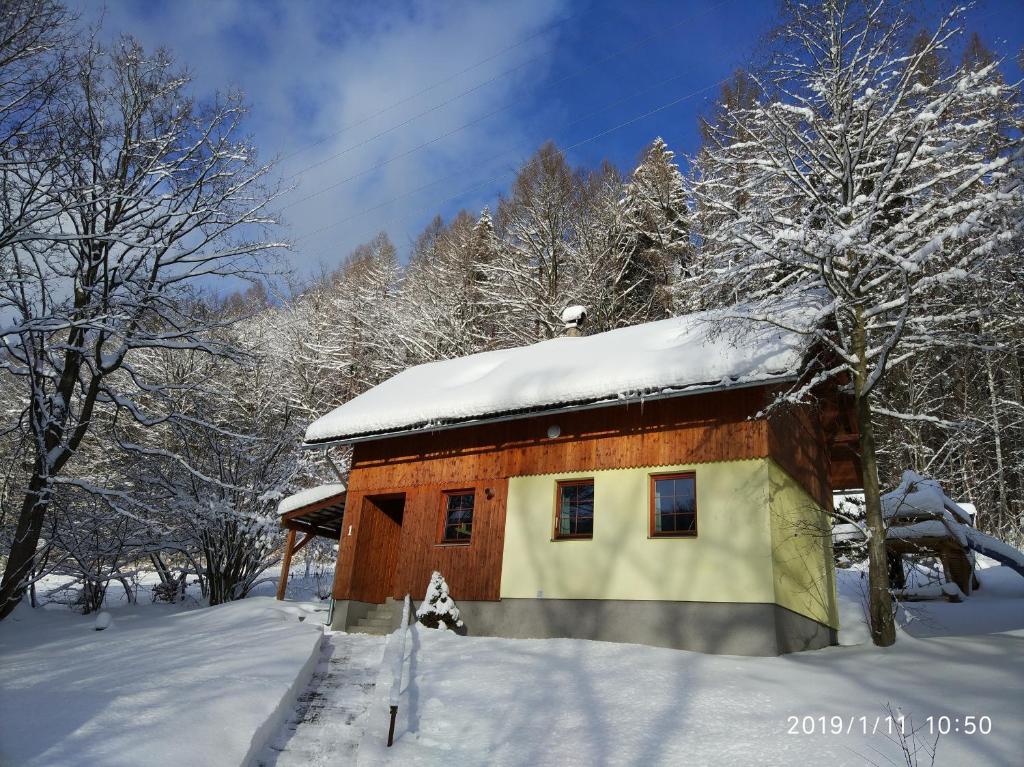 Cabaña de madera pequeña con nieve en el techo en Chata Koutík en Loučná nad Desnou