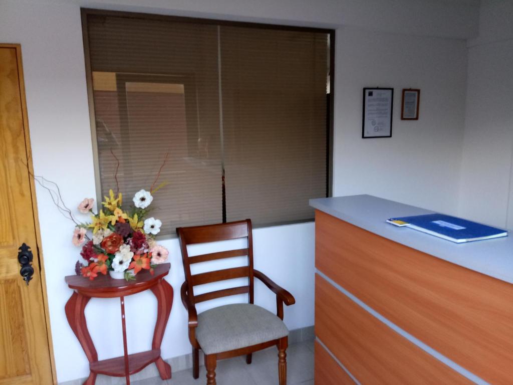 einen Stuhl und einen Tisch mit einer Blumenvase in der Unterkunft Casa Huespedes Angoba in Arica