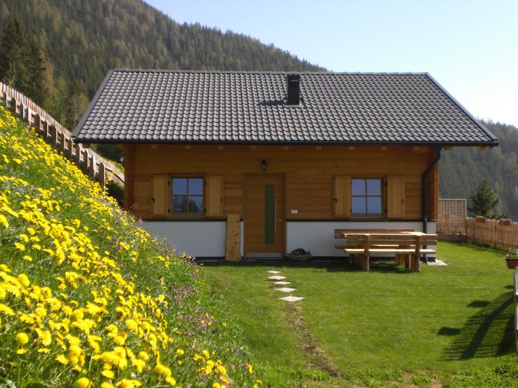 a wooden cabin with a picnic table and a field of flowers at Chalet Niederhaushof in Ultimo