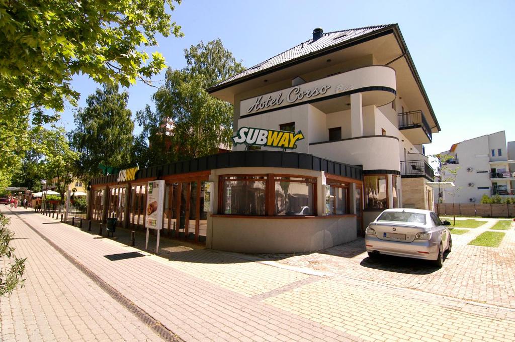 un edificio con un coche aparcado delante de él en Hotel Corso en Siófok