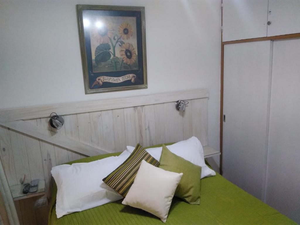 1 cama con 4 almohadas y una foto en la pared en Estudio en Edificio Olagüe en Mar del Plata