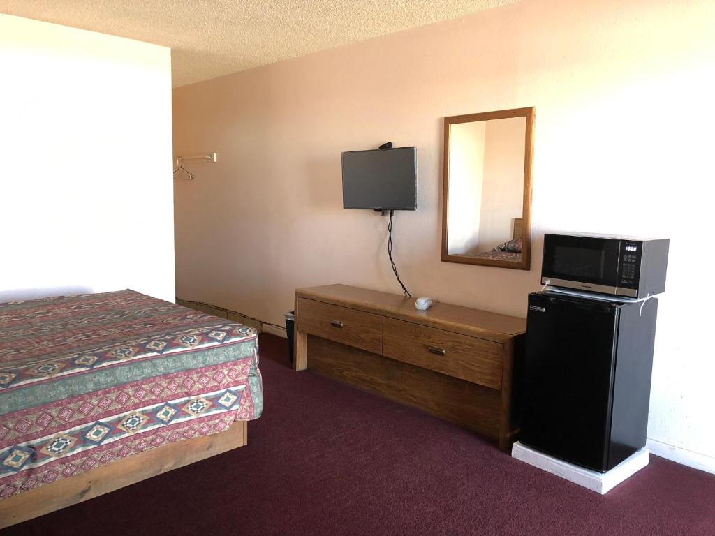 a bedroom with a bed and a dresser with a television at Deluxe Inn Motel in Sparks