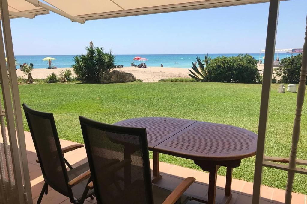 a table and chairs on a porch with a view of the beach at Amazing in front of the sea apartment in Comarruga