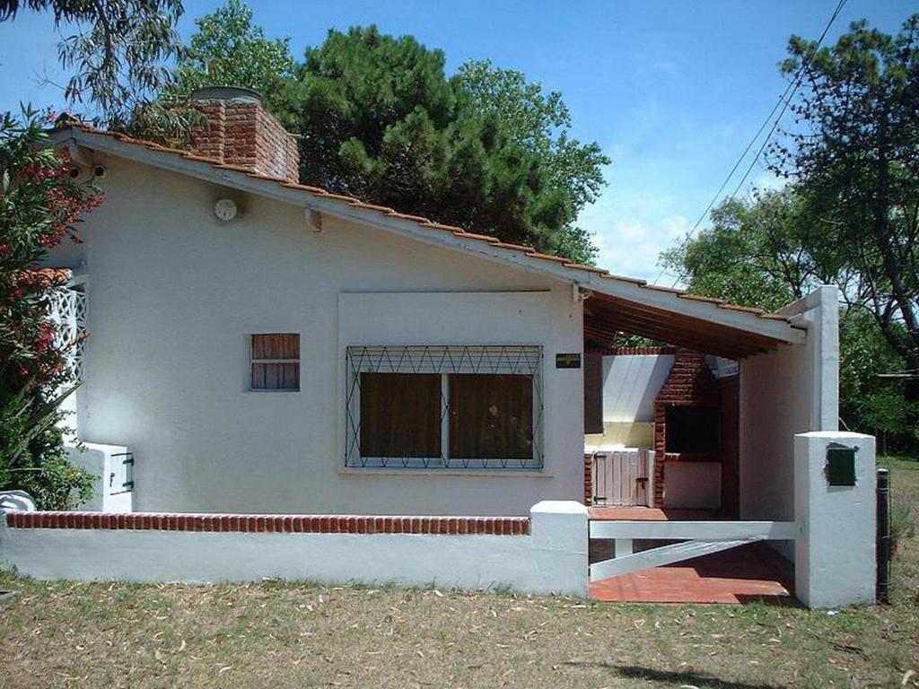 una pequeña casa blanca con ventana y porche en la Avenida 2, 3344 de Villa Gesell