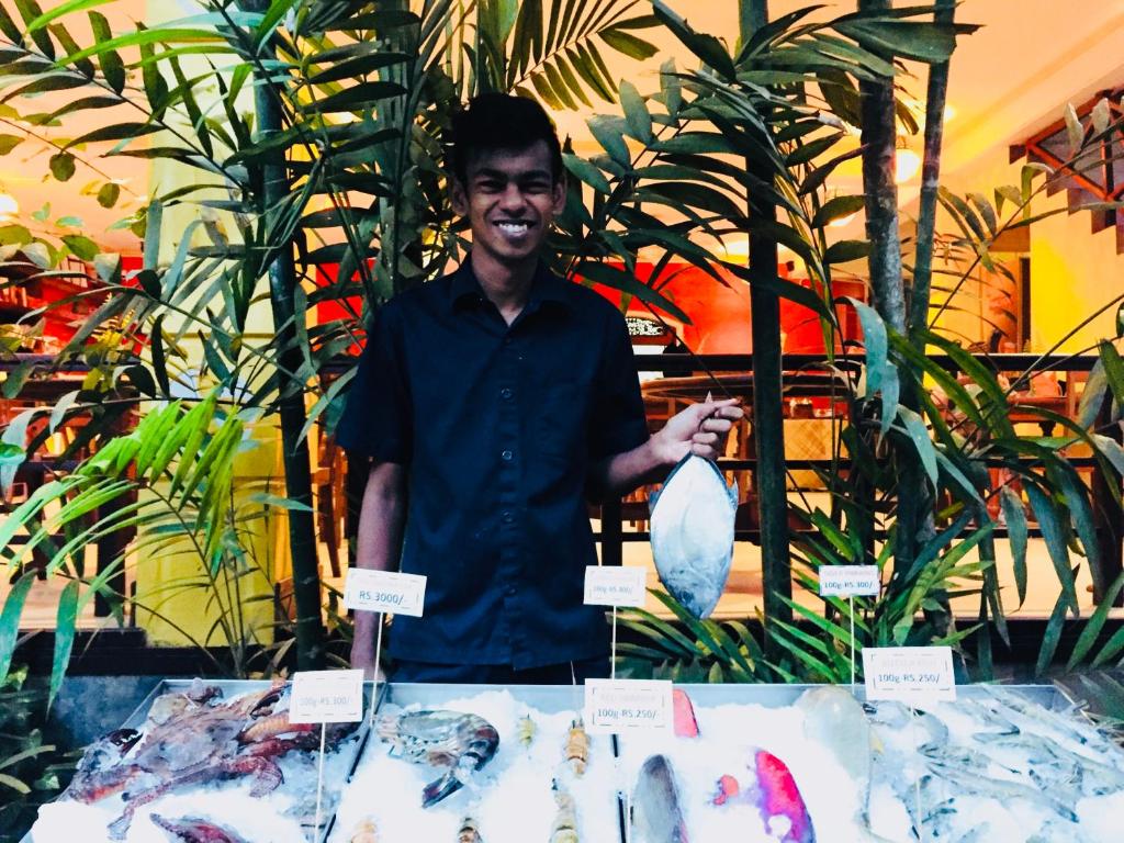 a man standing in front of a table with a vase at Thambapanni Retreat in Unawatuna