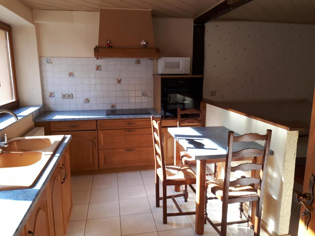 een keuken met een tafel en stoelen en een wastafel bij Le moulin des automates in Fréland