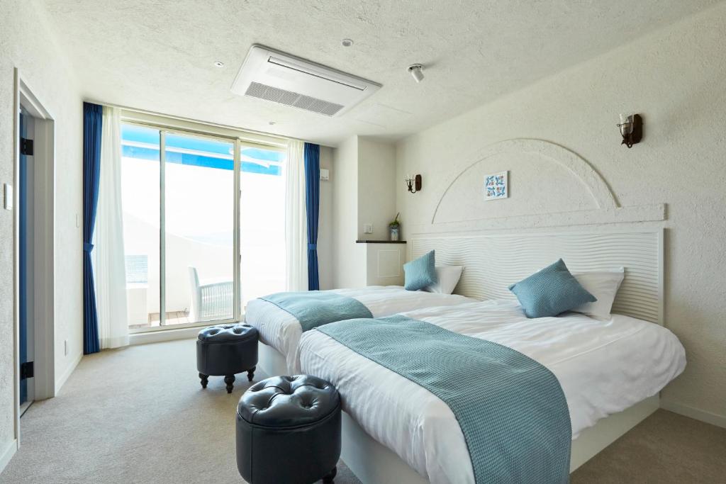 a bedroom with two beds and a large window at Wakanoura Nature Resort Epicharis in Wakayama