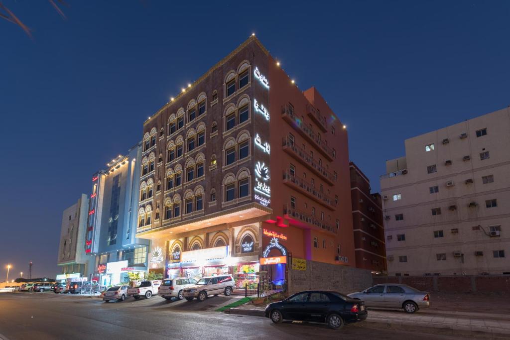 Un grand bâtiment avec des voitures garées dans un parking dans l'établissement Rose Suite Operated by Suite Hotel Management, à Djeddah