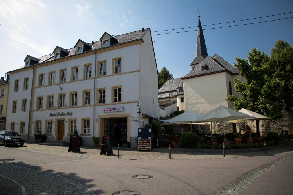 ein großes weißes Gebäude mit einem Kirchturm auf einer Straße in der Unterkunft Hotel Perler Hof in Perl