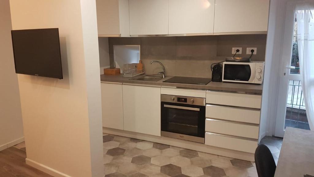 a kitchen with white cabinets and a microwave at Varenna Sweet Home in Varenna