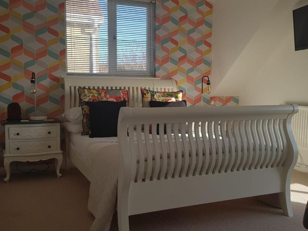 a bedroom with a white crib and a window at Telscombe Cliffs Bed and Breakfast in Rottingdean