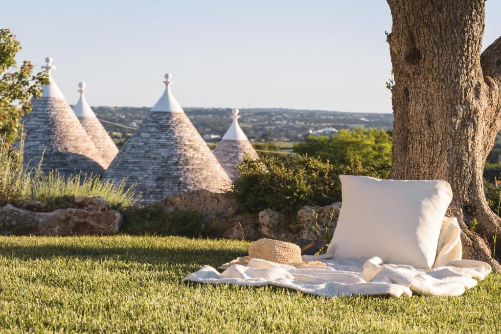 a pillow and a hat on a blanket next to a tree at Trulli Angela in Locorotondo